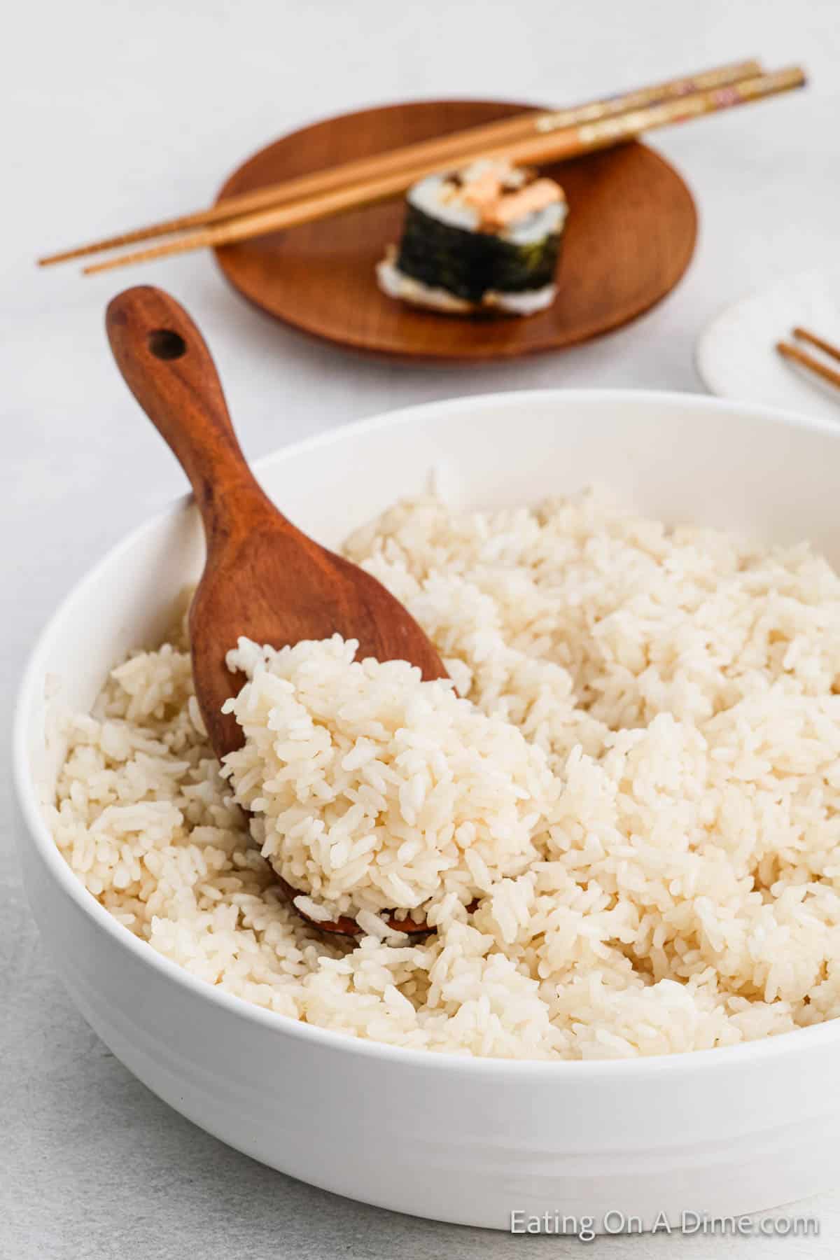 White Rice in a white bowl with a serving on a wooden spoon