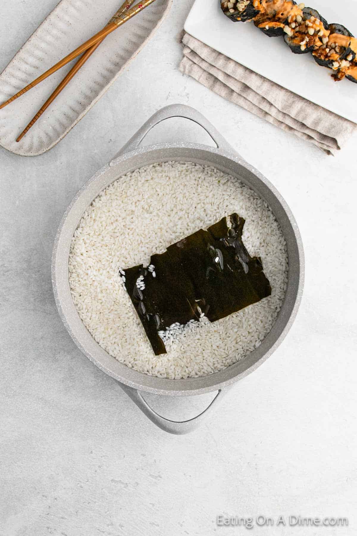 White rice in a large saucepan with a piece of Kombu on top