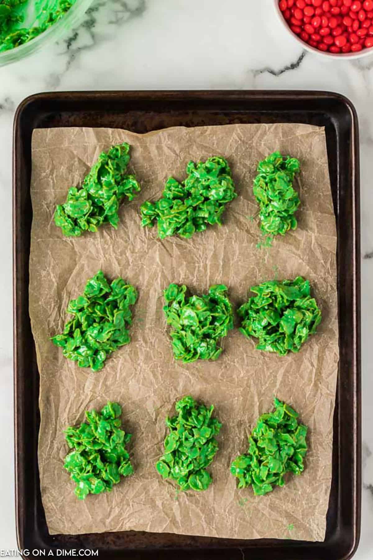 Green cereal mixture combined together in 6 piles on a baking sheet lined with parchment paper