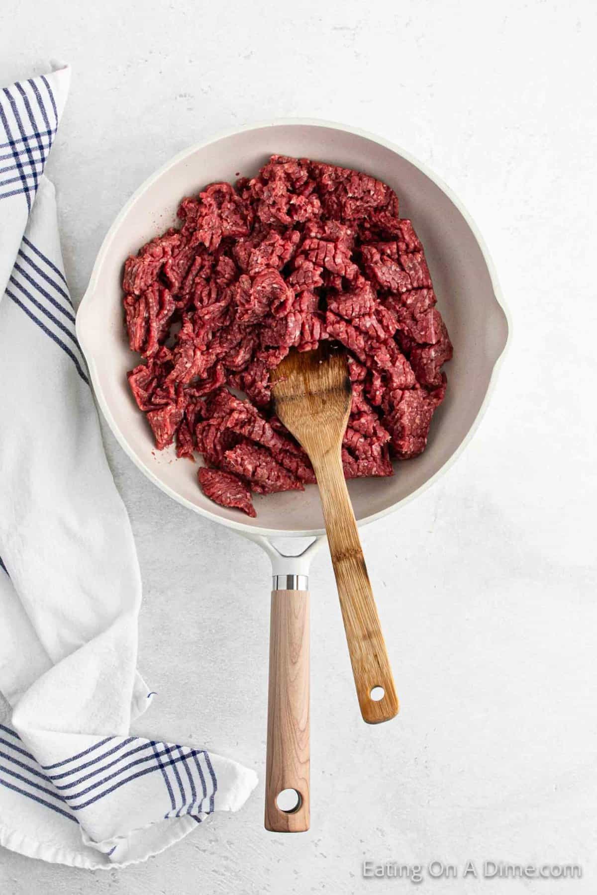 Cooking ground beef in a skillet with a wooden spoon