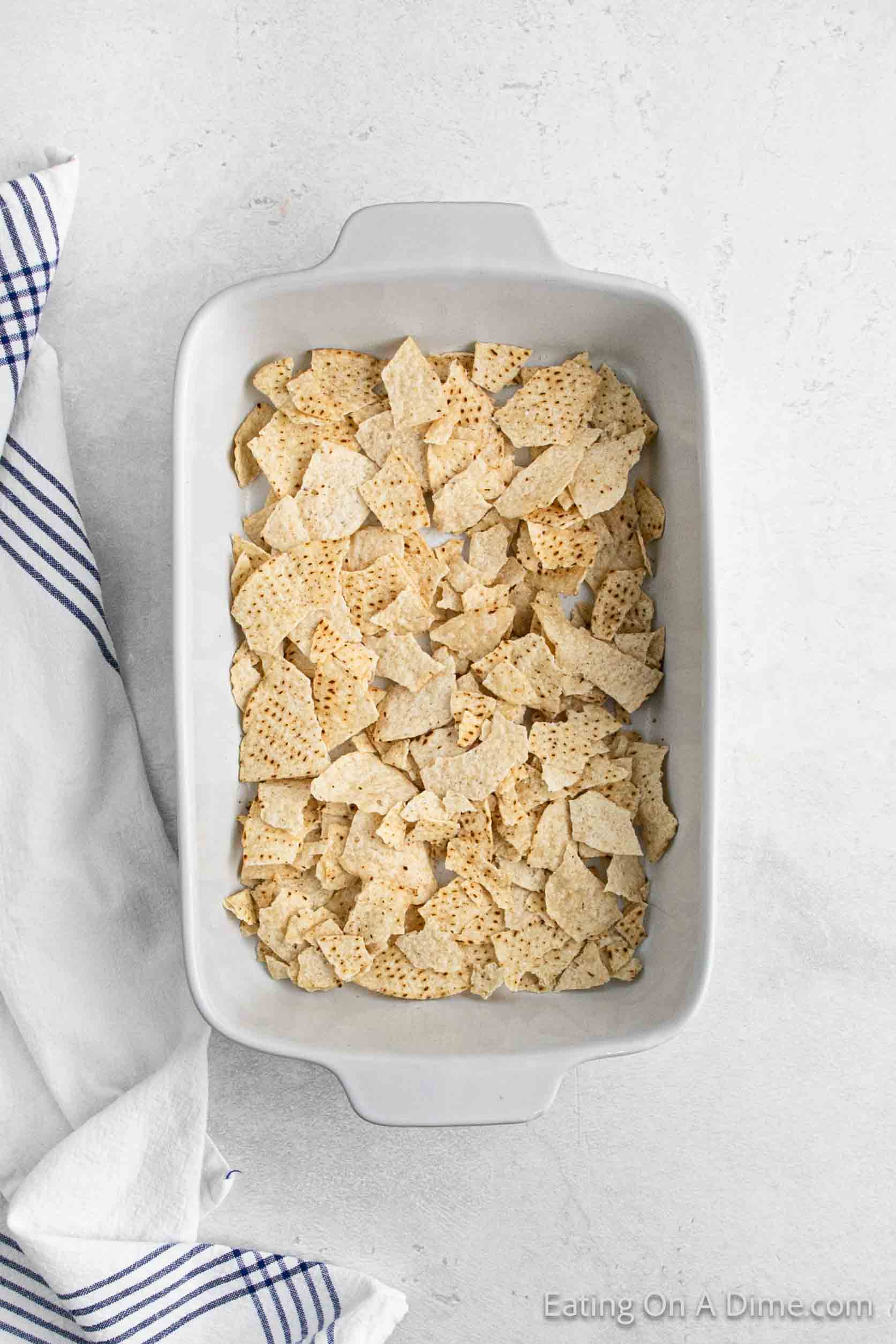 Crushed tortilla chips layered in a baking dish