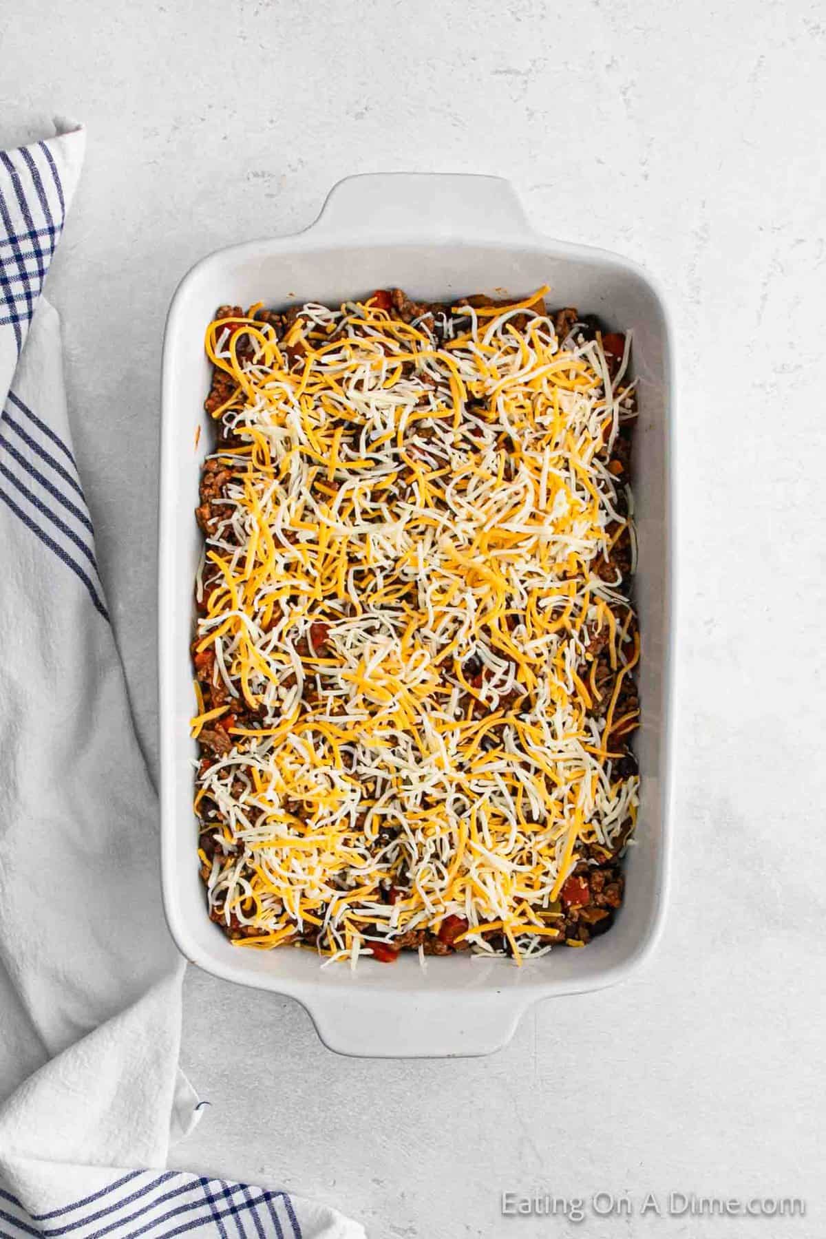 Topping ground beef mixture with shredded cheese