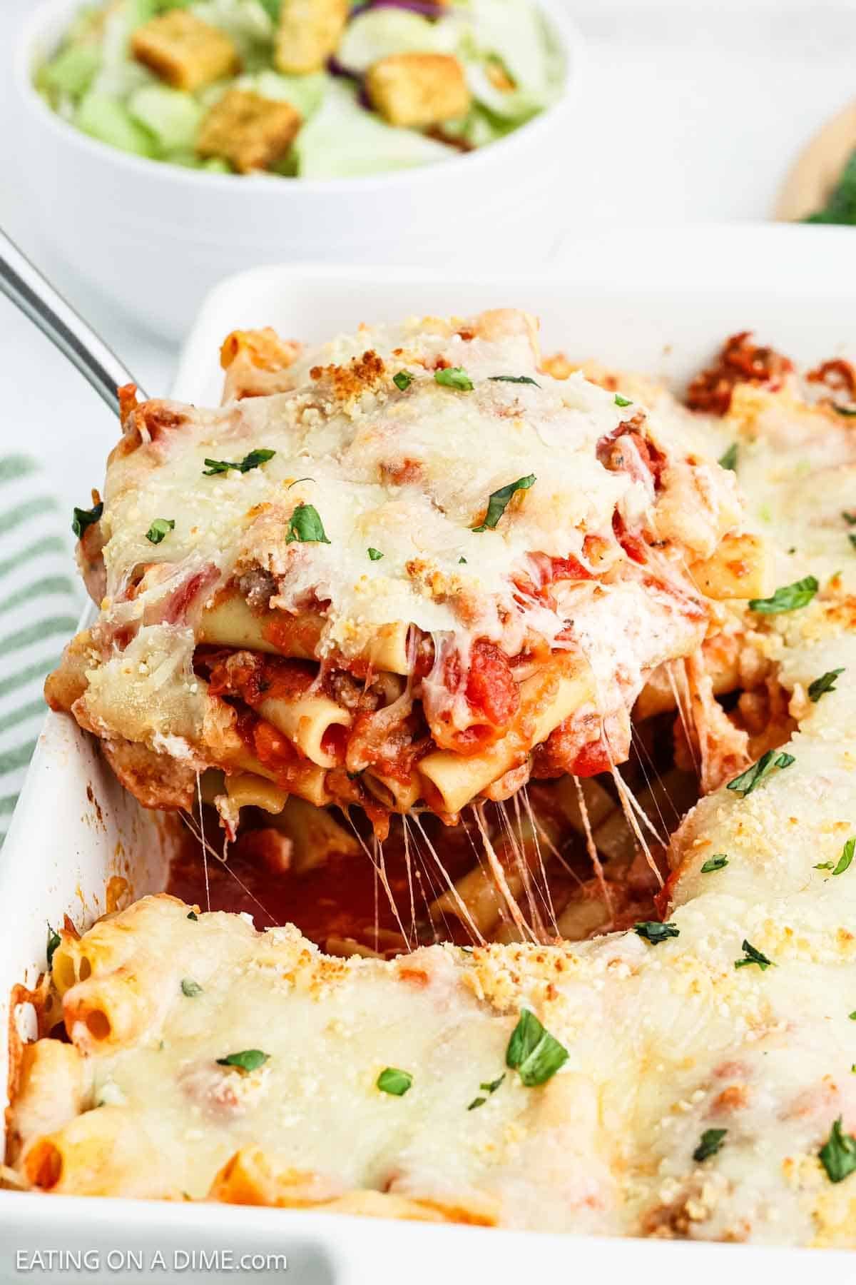 Baked Ziti in a casserole dish with a serving on a silver spatula