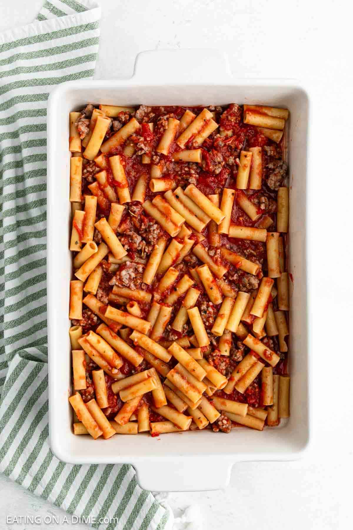 Layering a small portion of the ziti pasta mixture in a baking dish