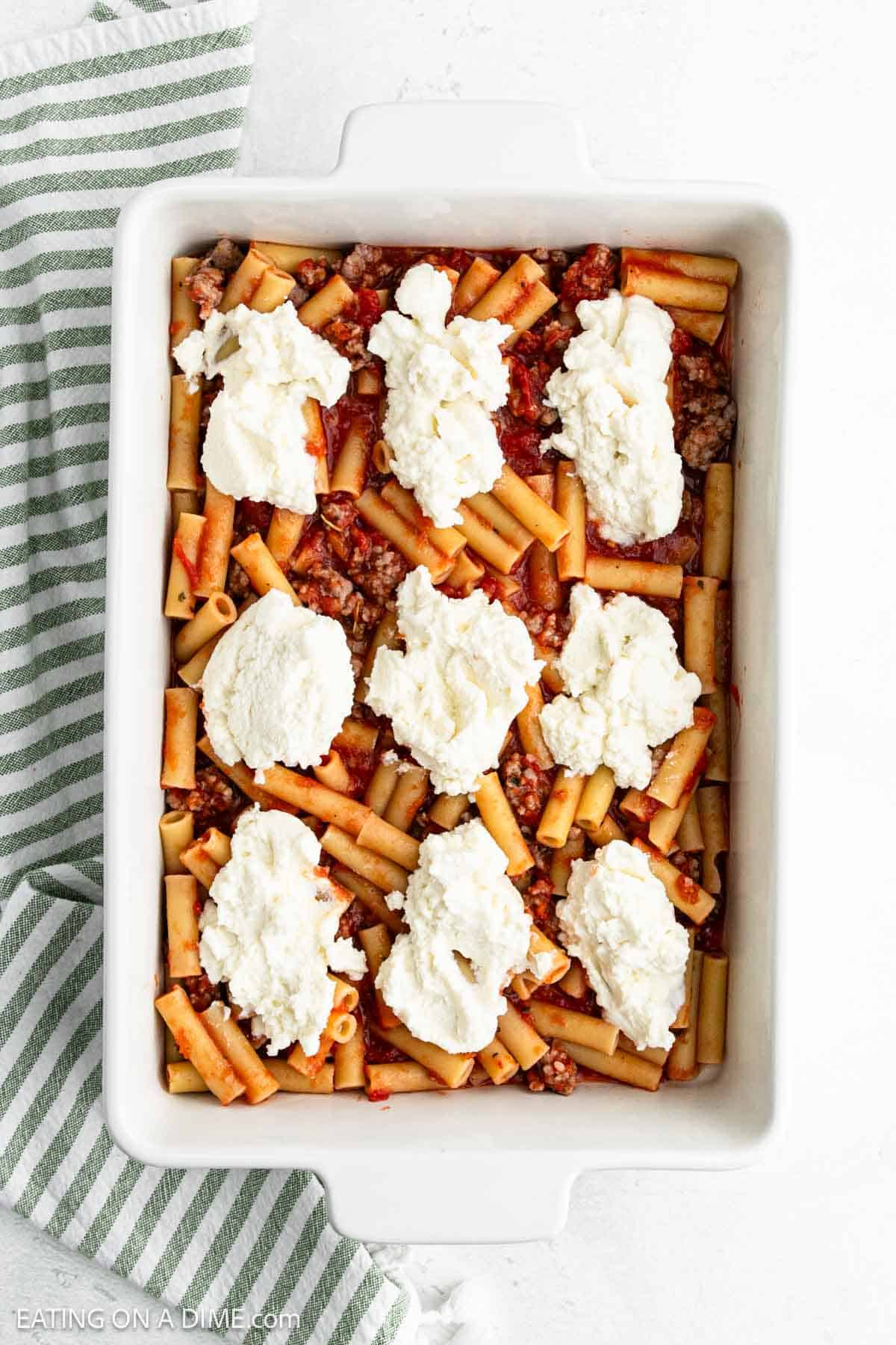 Topping Ziti Mixture in the baking dish topped with the Ricotta Cheese