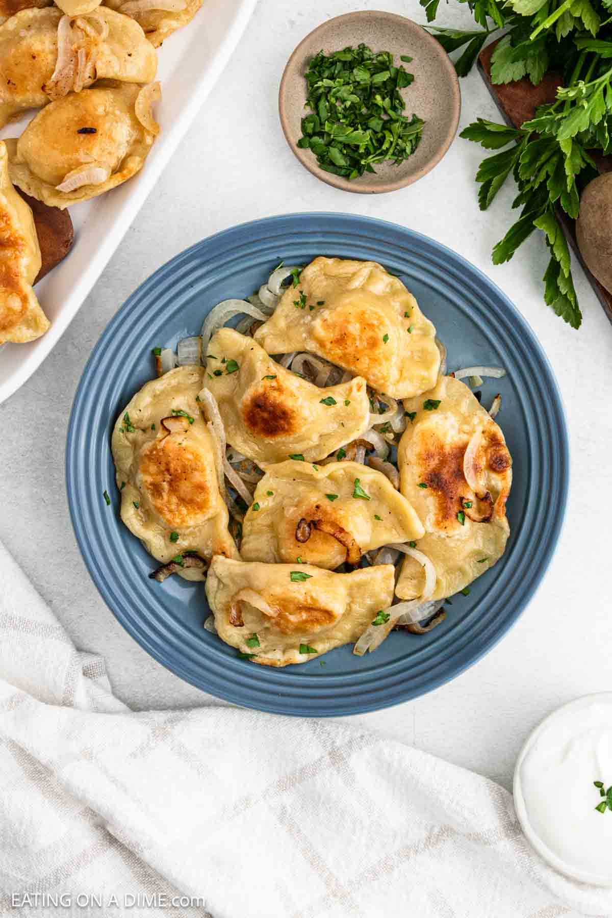 Pierogi cooked golden brown stacked on a plate with cooked onions