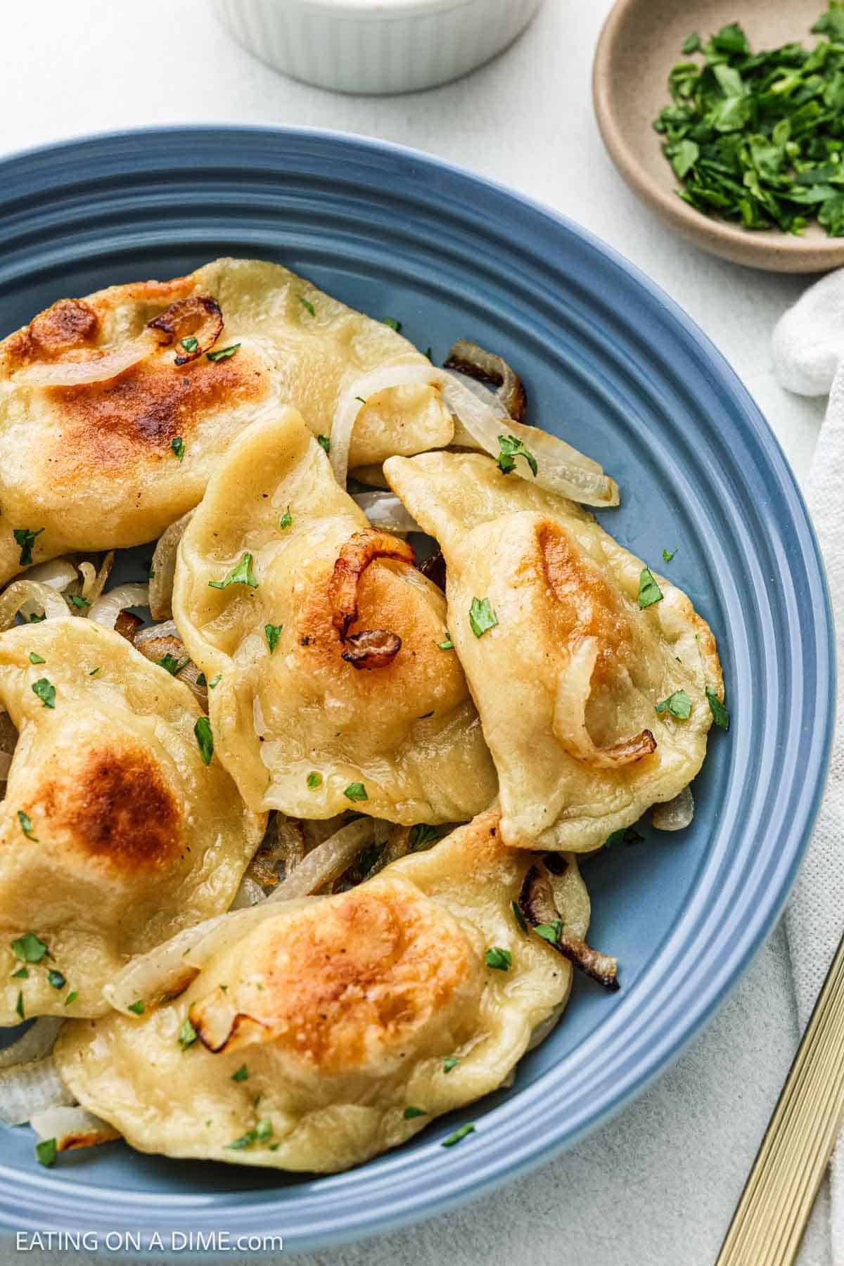 Pierogi cooked golden brown on a plate with cooked onions