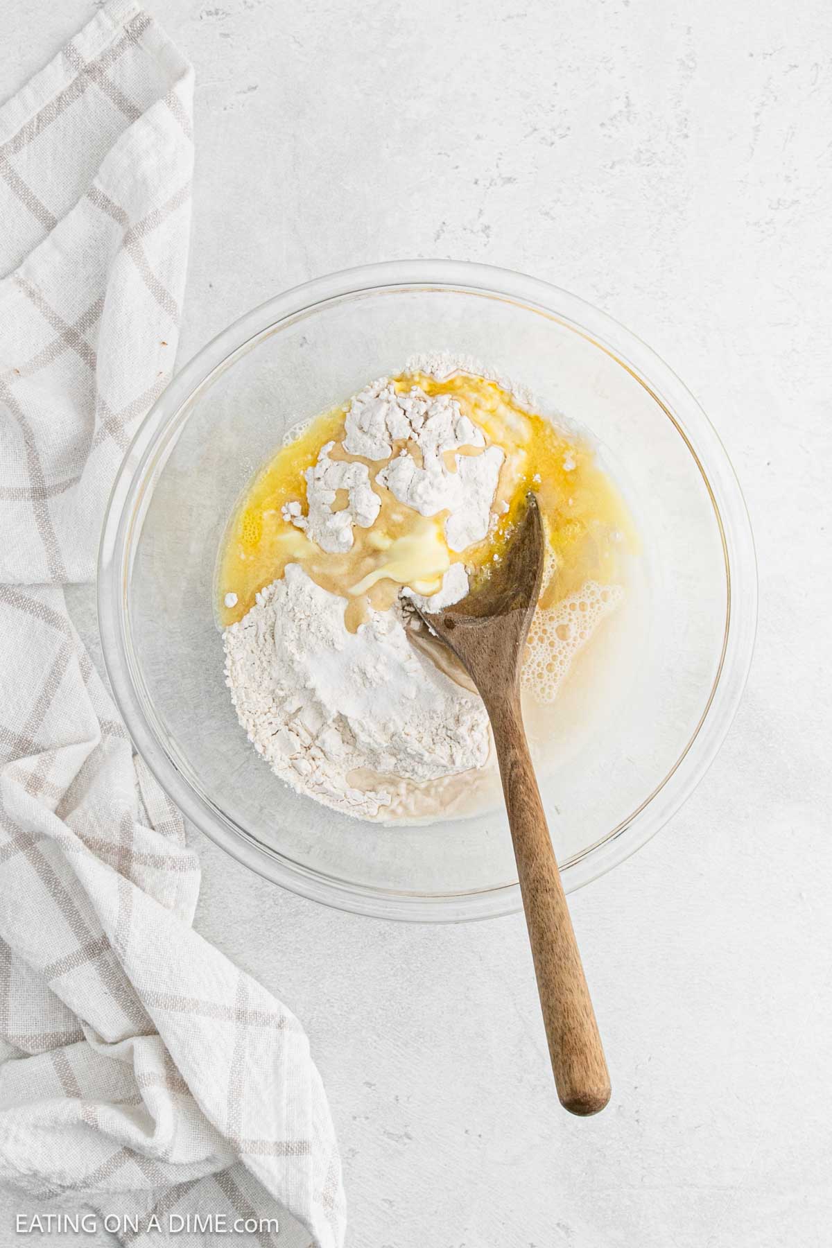 Combining egg, flour, oil, salt, and water in a bowl with a wooden spoon