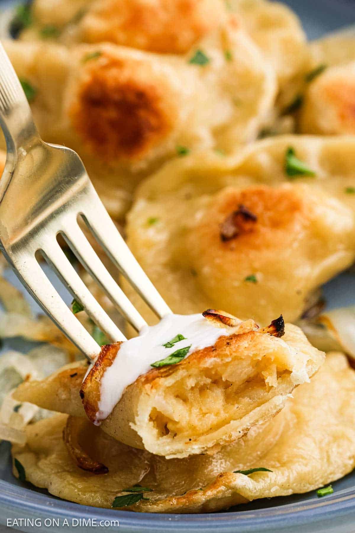 Golden Brown Pierogi with a fork topped with sour cream