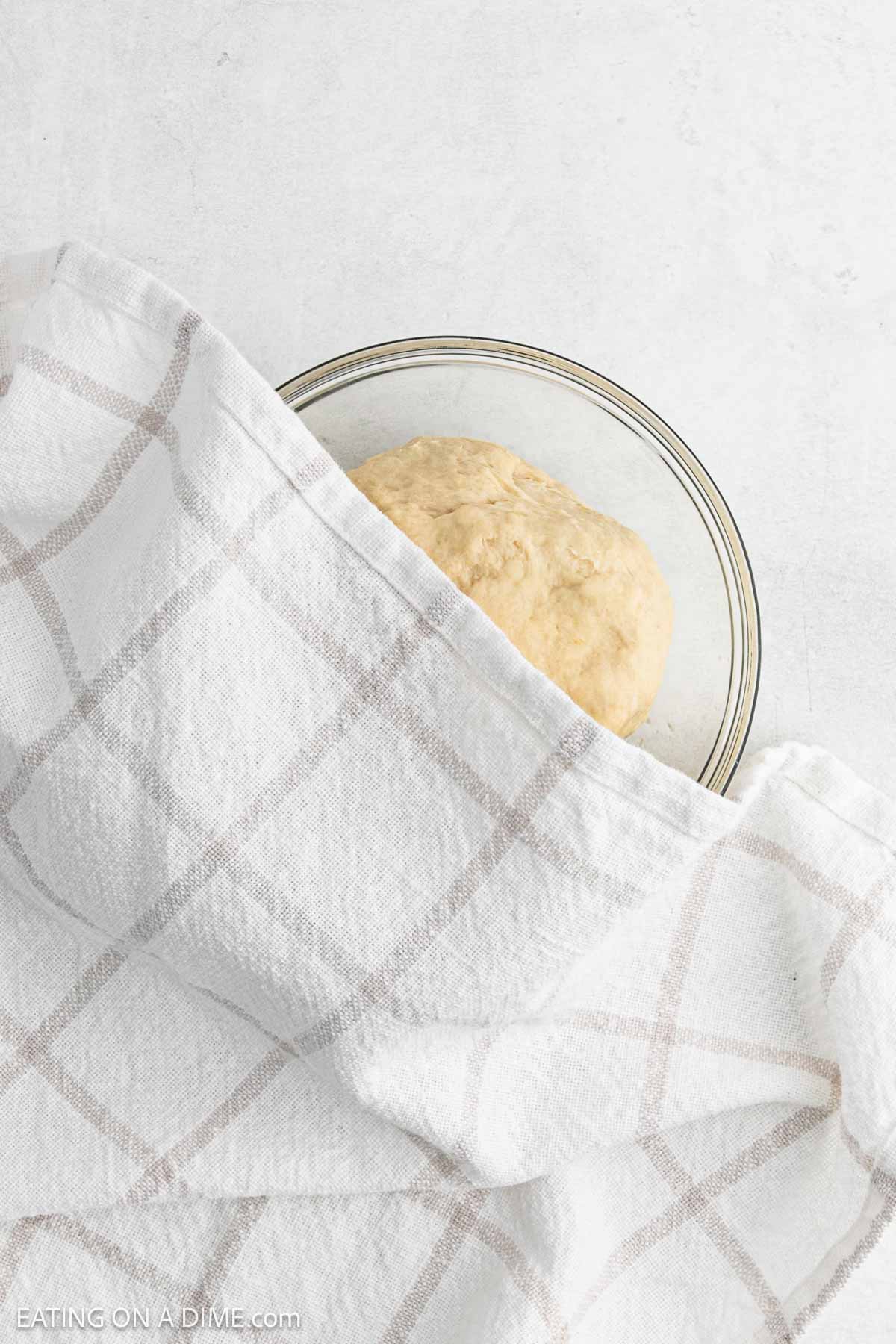 Prepared dough in a bowl covered with a towel