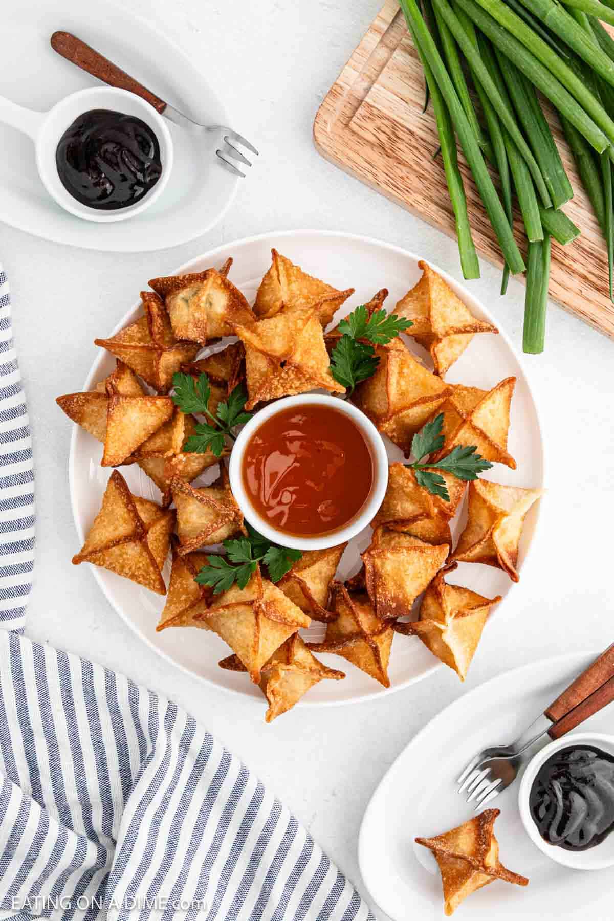 Cooked crab rangoon on a platter with bowls of dipping sauce