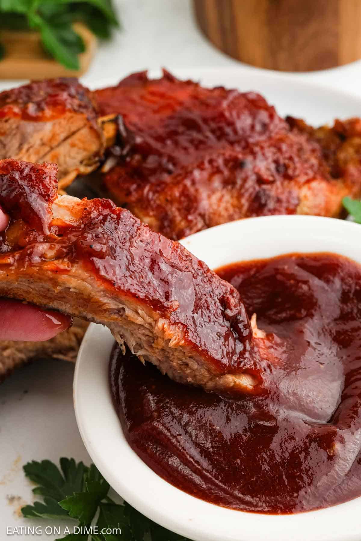 Slice BBQ Ribs dipped into a bowl of BBQ Sauce