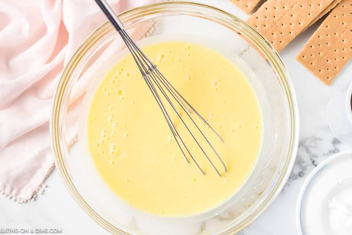 Combining the pudding mix, milk, and cool whip in a bowl with a whisk