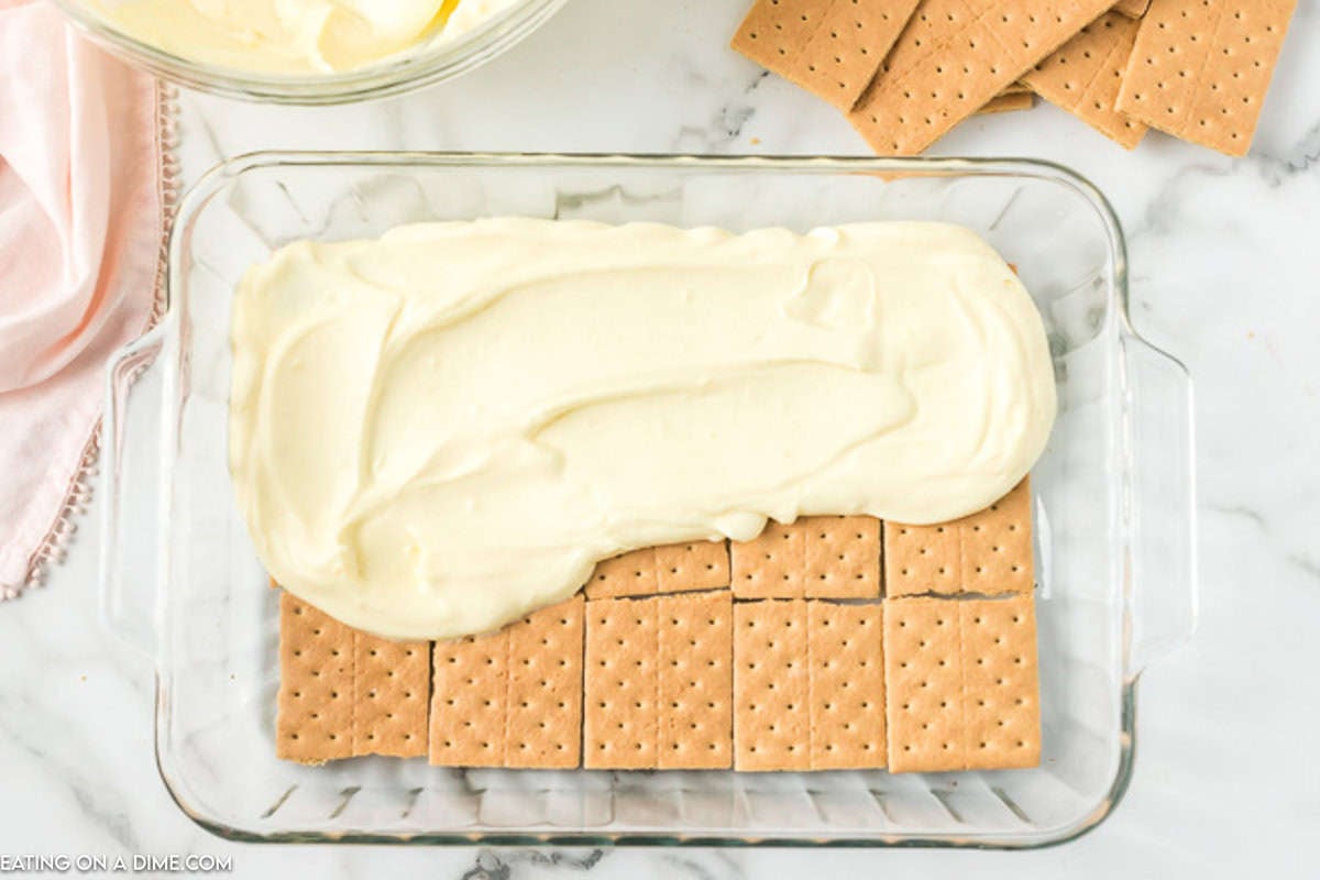 Spreading the pudding mix over the graham crackers in a baking dish