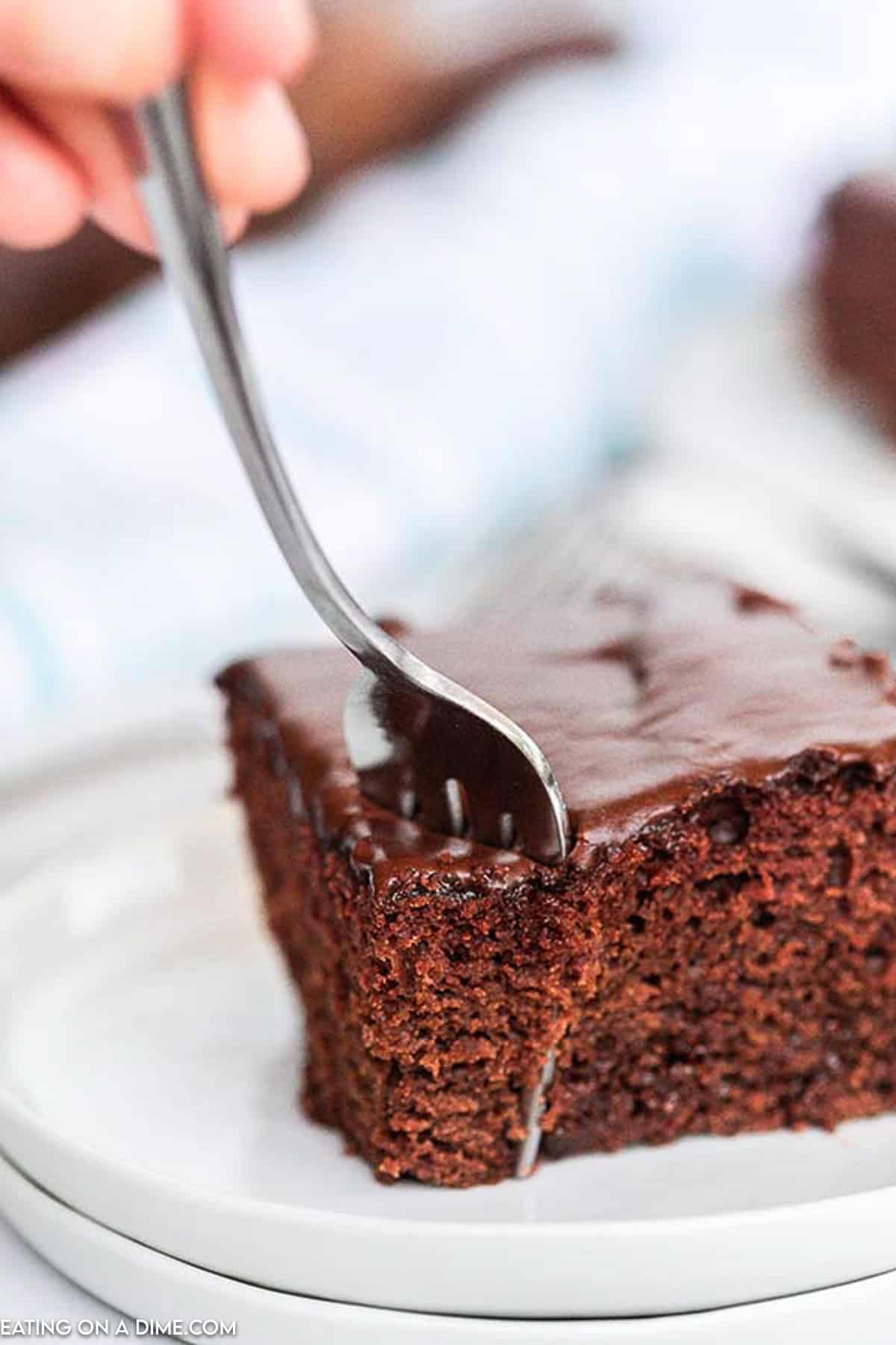 Slice of chocolate cake with a fork inserted into the cake 