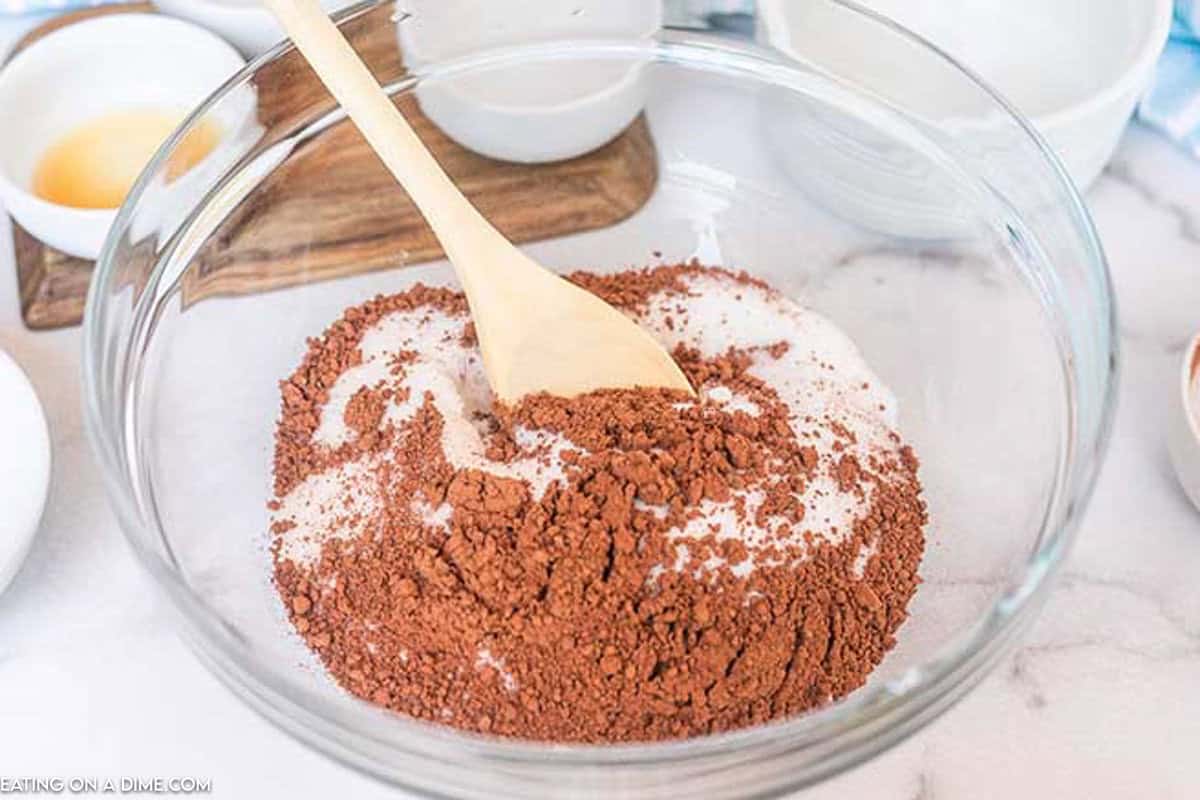 Cocoa Powder, flour, and sugar in a bowl with a wooden spoon