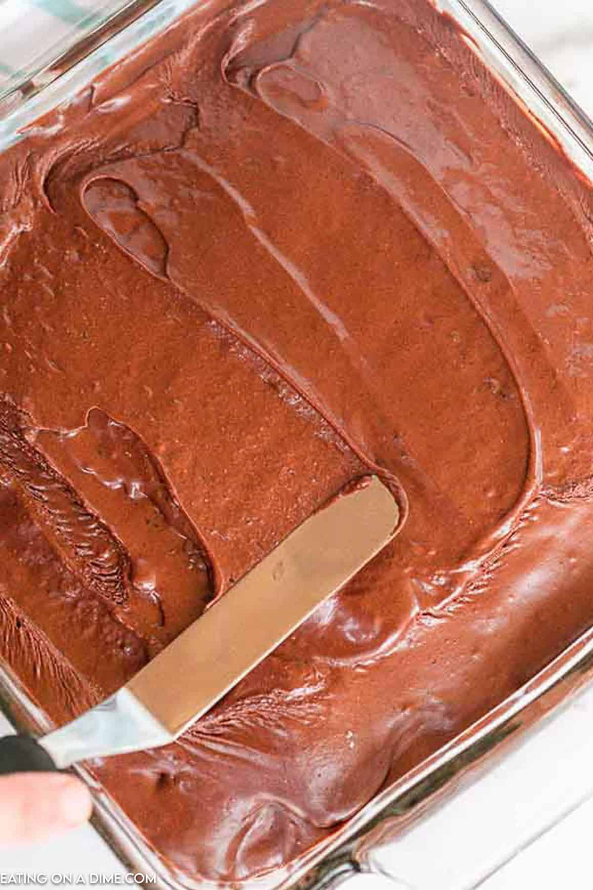 Spreading the chocolate frosting over the cake with a spatula